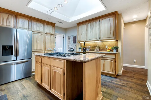 a kitchen with granite countertop wooden cabinets and refrigerator
