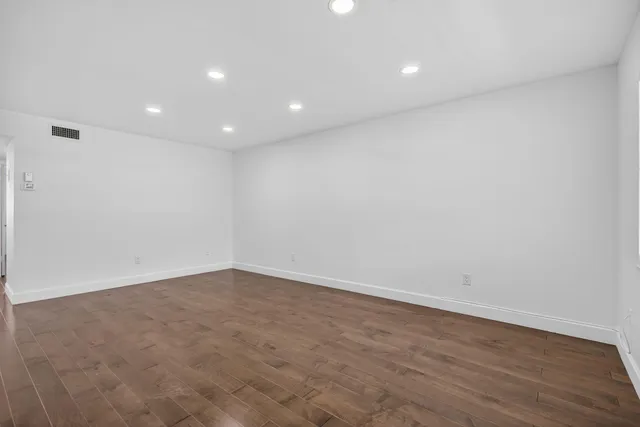 a view of an empty room with a window and wooden floor