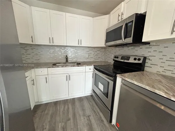 a kitchen with stainless steel appliances granite countertop white cabinets sink and stove