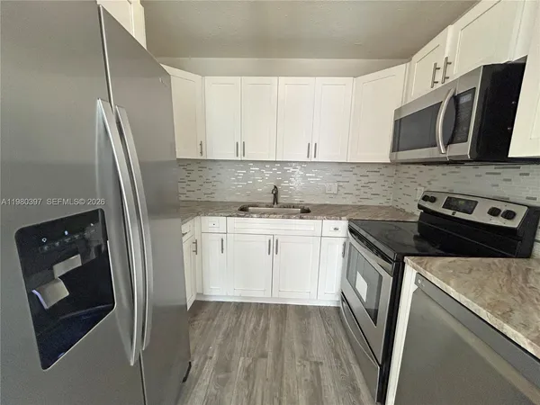 a kitchen with granite countertop a sink stove and refrigerator