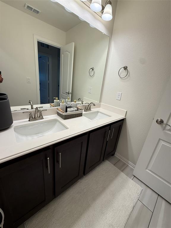 5212 Troupe Road McKinney, TX 75071 - Photo 24 of 38 Dual vanity featuring dark wood-finish cabinetry, white countertops, and undermount sinks