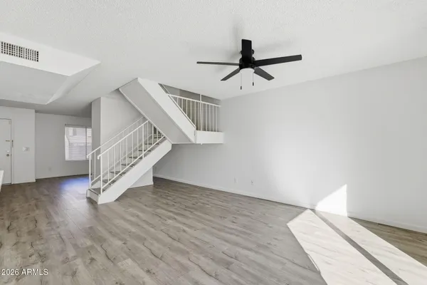 a view of an empty room with wooden floor and stairs