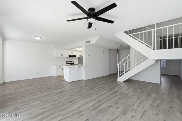 a view of empty room with wooden floor and ceiling fan