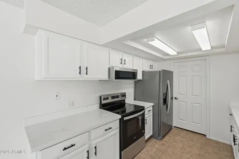 a kitchen with stainless steel appliances a refrigerator stove and white cabinets