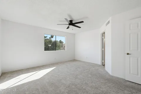 an empty room with windows and ceiling fan