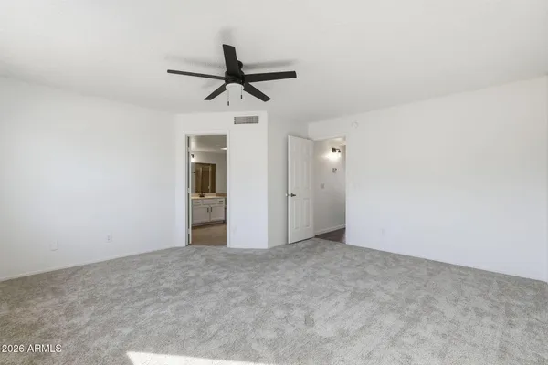 an empty room with chandelier fan and windows