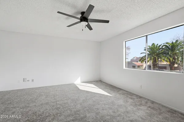 an empty room with window and a ceiling fan