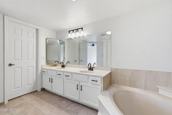 a spacious bathroom with a double vanity sink a mirror and a bathtub