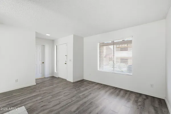 a view of an empty room with wooden floor and a window