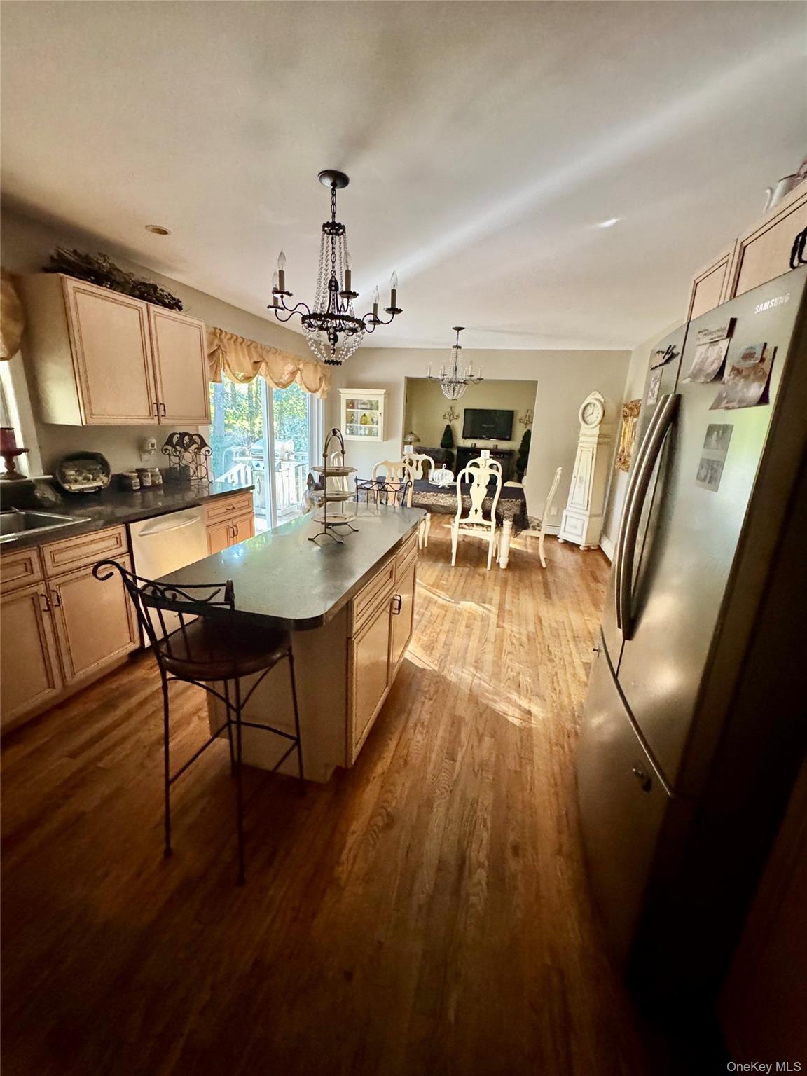 43 North Cozine Road Manorville, NY 11949 - Photo 14 of 42 Kitchen featuring stainless steel appliances, light brown cabinets, dark countertops, a center island with sink, and hanging light fixtures