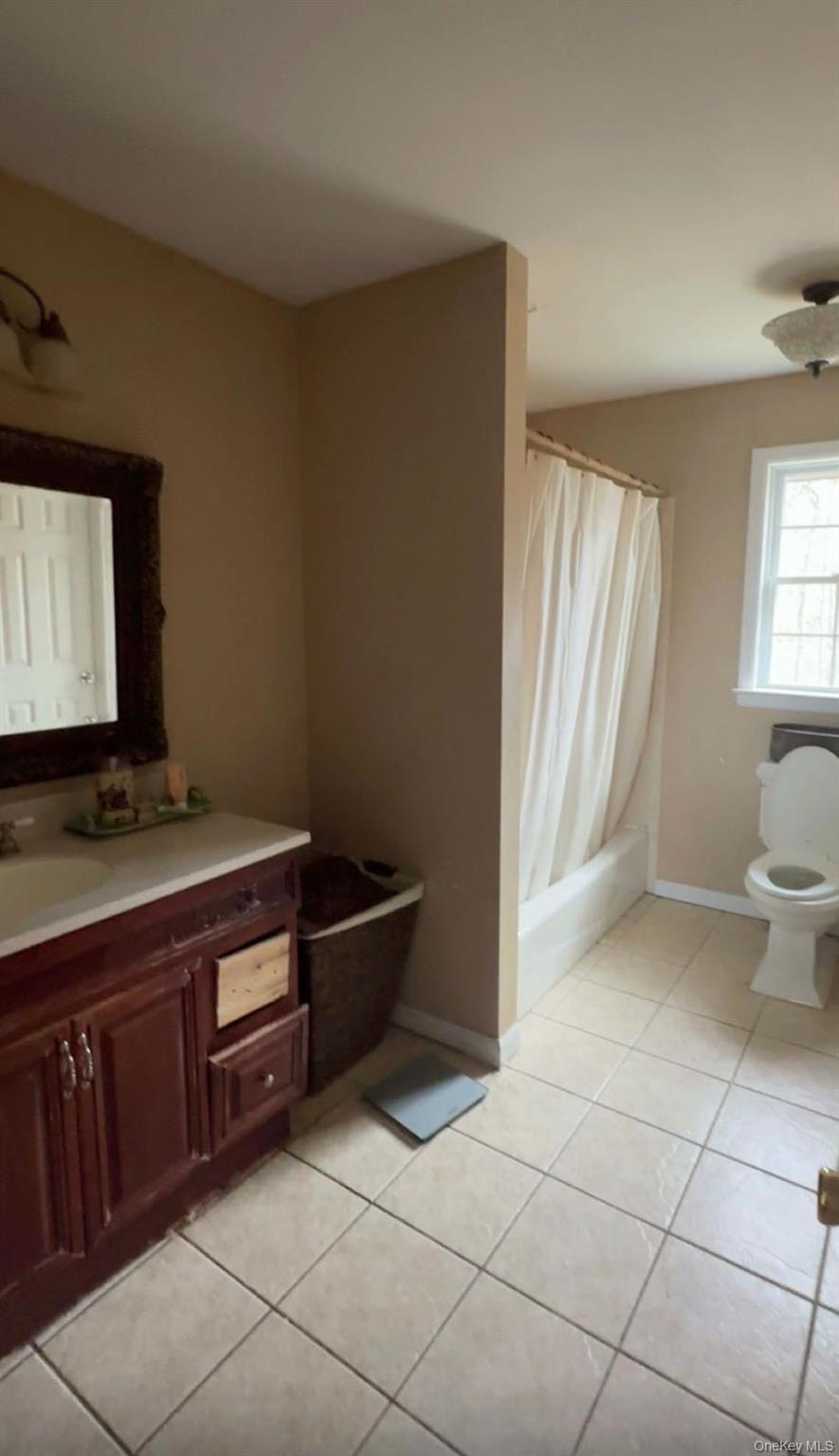 43 North Cozine Road Manorville, NY 11949 - Photo 22 of 42 Bathroom featuring light tile patterned floors, shower / bath combination with curtain, and vanity