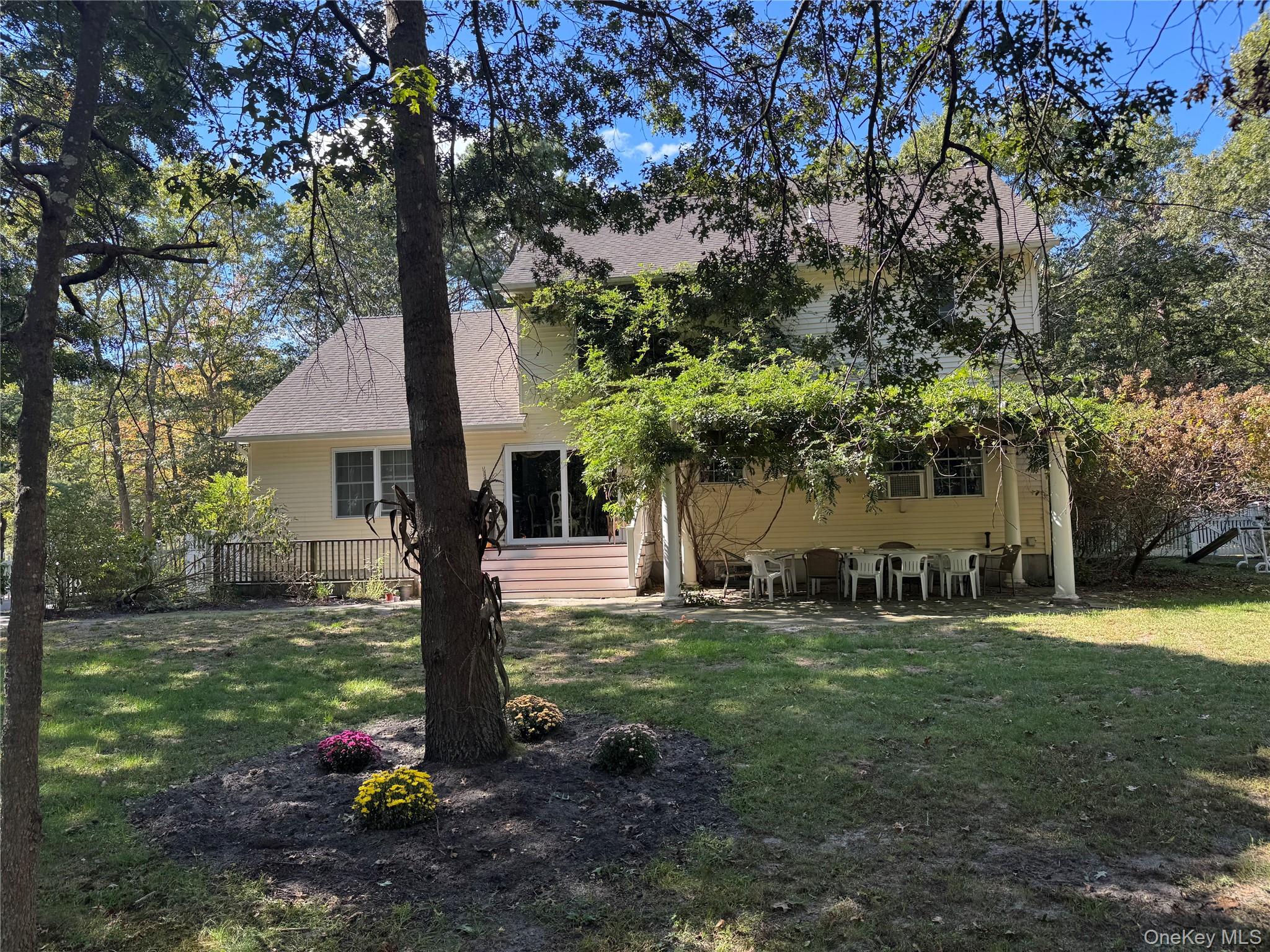 43 North Cozine Road Manorville, NY 11949 - Photo 41 of 42 Rear view of house with a yard, a patio area, and roof with shingles