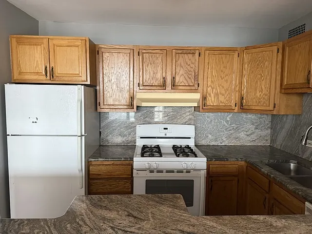 a kitchen with granite countertop a refrigerator sink and cabinets
