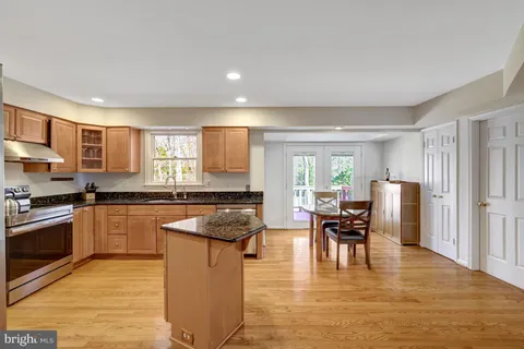 a kitchen with stainless steel appliances granite countertop wooden cabinets a stove a sink a dining table and chairs