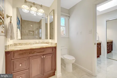 a bathroom with a granite countertop sink a toilet and a mirror