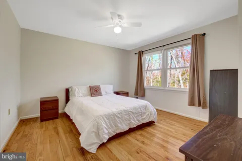 a bedroom with a bed and a large window with wooden floor