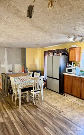 a kitchen with stainless steel appliances granite countertop a stove a refrigerator a sink a dining table and chairs with wooden floor
