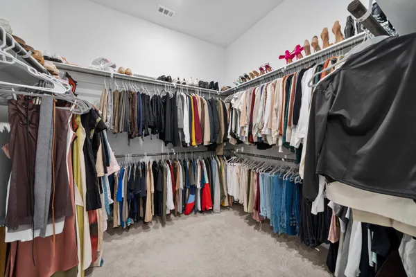 a view of walk in closet with clothes and shoes