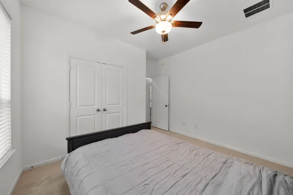 a bedroom with a large bed and a chandelier fan