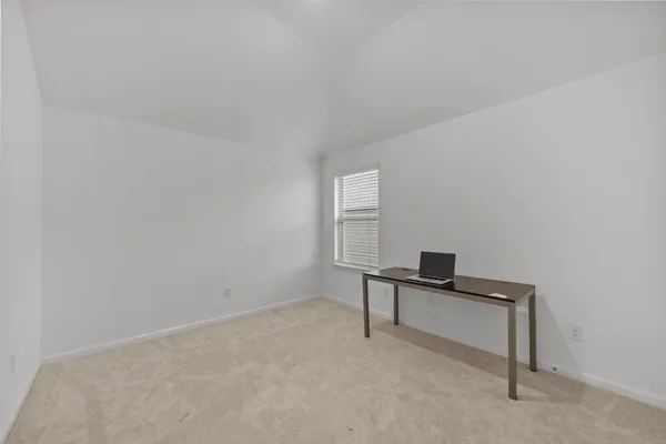 a room with a bed and a desk with stool