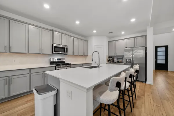 a kitchen with a sink a stove a refrigerator cabinets and a dining table