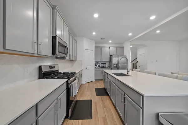 a kitchen with stainless steel appliances granite countertop a sink a stove top oven a counter space and cabinets