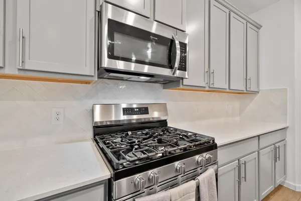 a kitchen with stainless steel appliances granite countertop white cabinets and a stove top oven