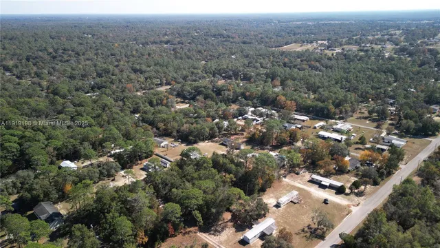 an aerial view of residential house with outdoor space and trees all around