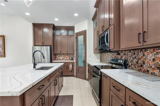 a kitchen with stainless steel appliances granite countertop a sink a stove and a refrigerator