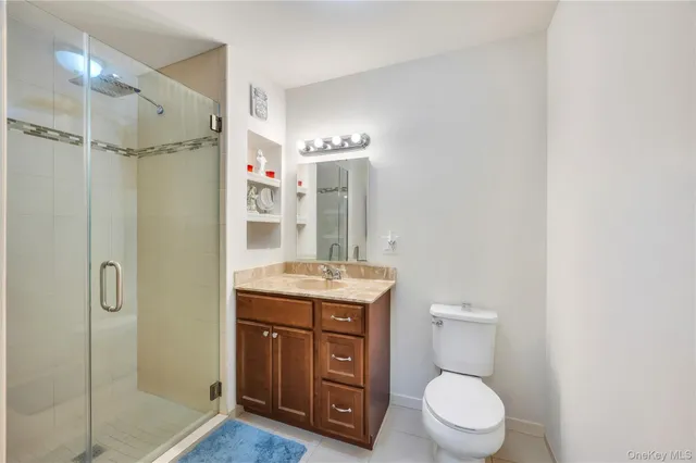 a bathroom with a granite countertop sink toilet a mirror a vanity and shower