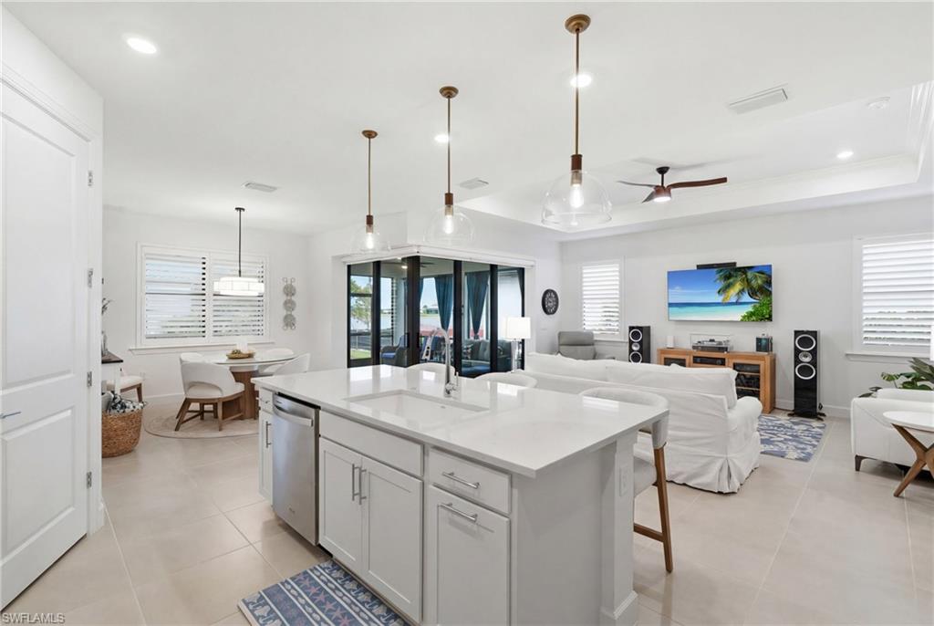 18364 Ridgeline Drive Estero, FL 33928 - Photo 16 of 50 a large kitchen with kitchen island a stove a sink a dining table and chairs