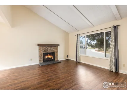 a view of an empty room with wooden floor fireplace and a window