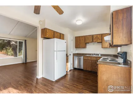 a kitchen with granite countertop a refrigerator a stove a sink and white cabinets with wooden floor