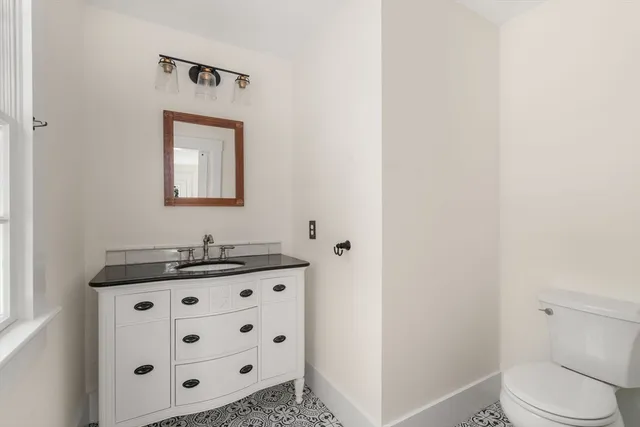 a bathroom with a granite countertop sink a toilet and mirror