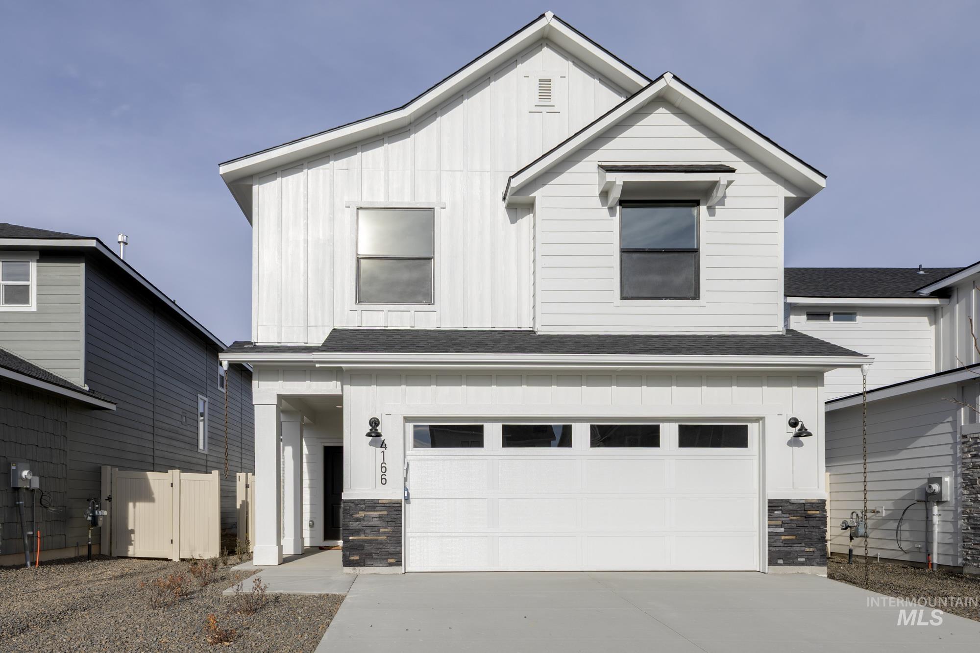 View of front facade with board and batten siding, stone siding, and a shingled roof