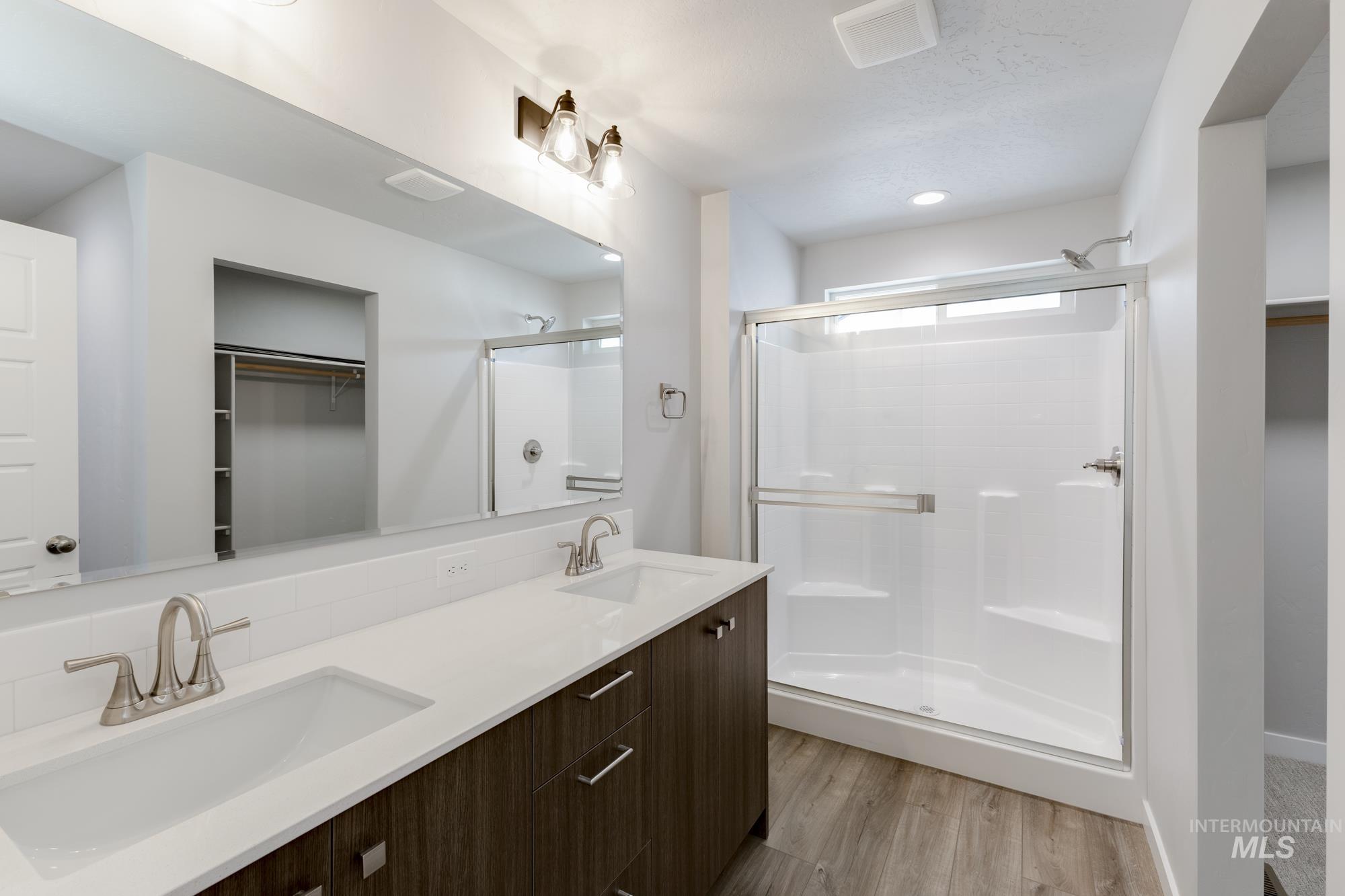 4166 East Kalinga Street Meridian, ID 83642 - Photo 19 of 22 Full bathroom featuring a spacious closet, double vanity, a shower stall, and light wood-style floors