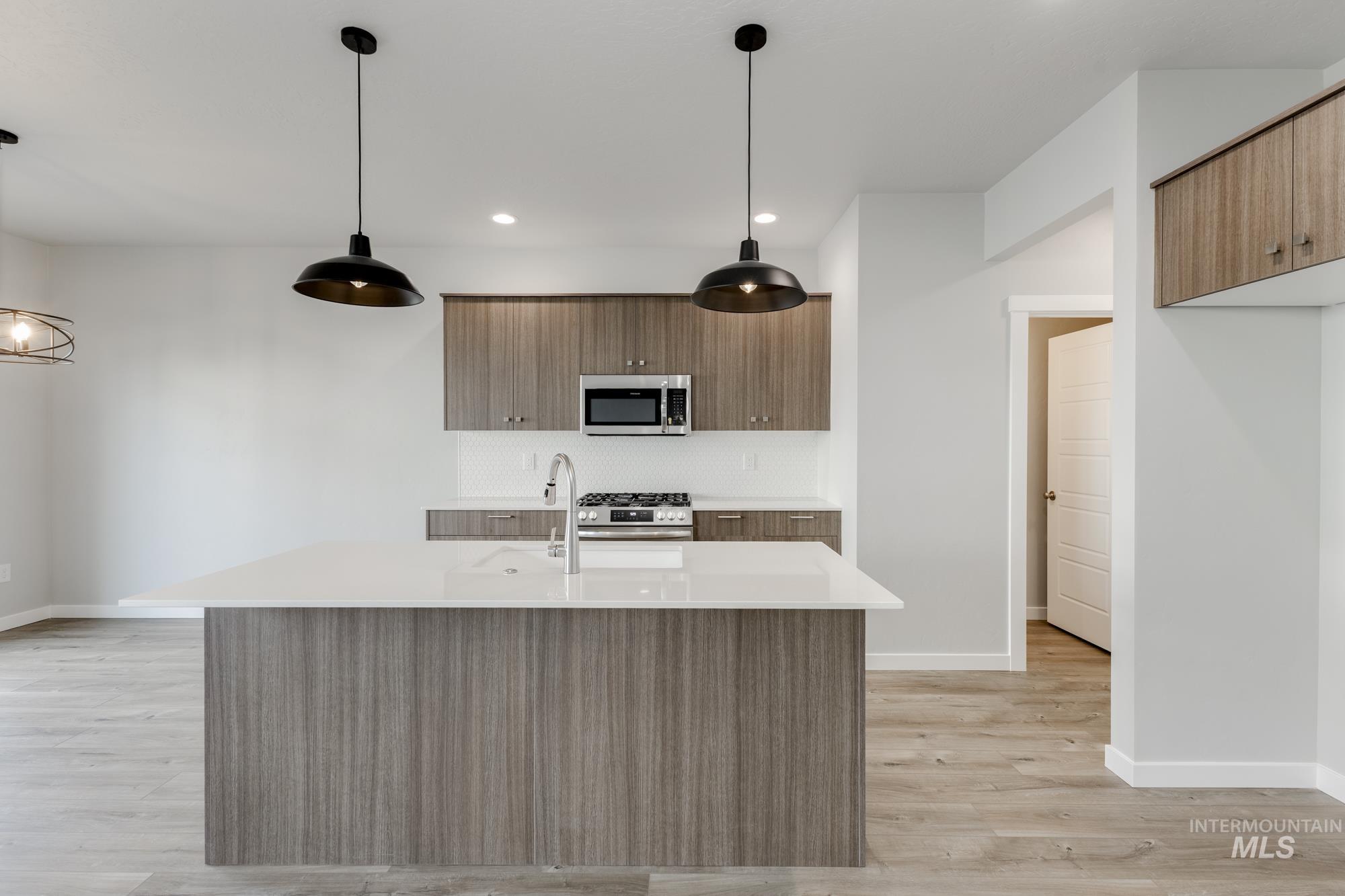 4166 East Kalinga Street Meridian, ID 83642 - Photo 4 of 22 Kitchen with hanging light fixtures, a center island with sink, light wood-style floors, modern cabinets, and stainless steel appliances