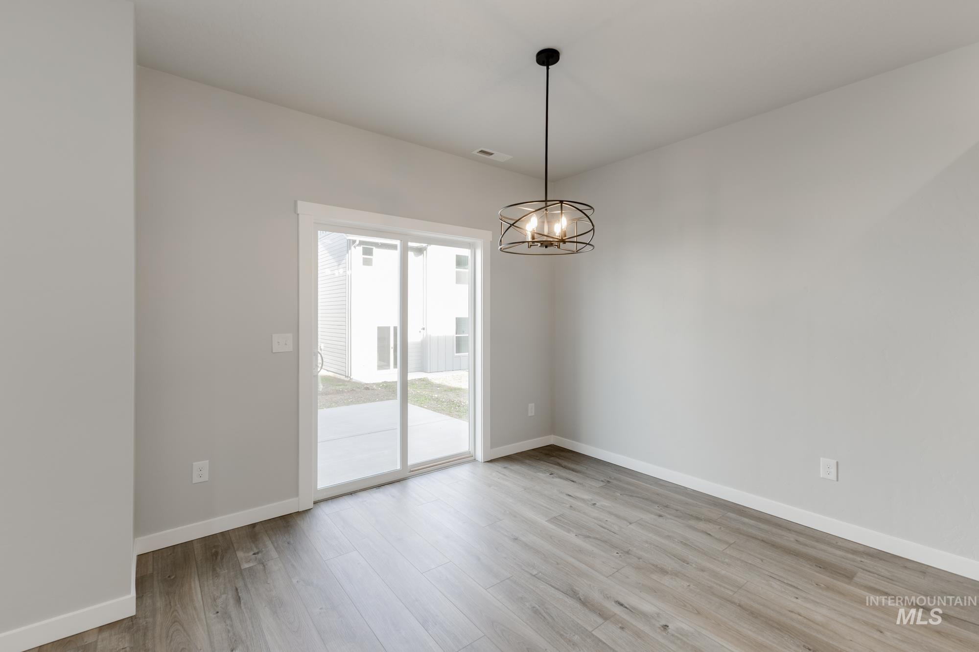4166 East Kalinga Street Meridian, ID 83642 - Photo 7 of 22 Empty room featuring light wood-style floors and a chandelier