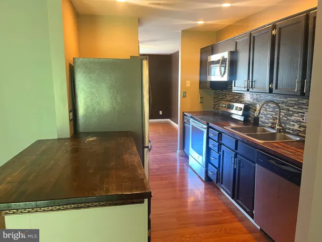 a kitchen with stainless steel appliances granite countertop a refrigerator a sink and wooden cabinets