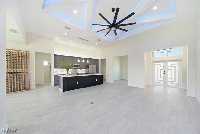 a living room with stainless steel appliances kitchen island granite countertop a sink a counter space and a window