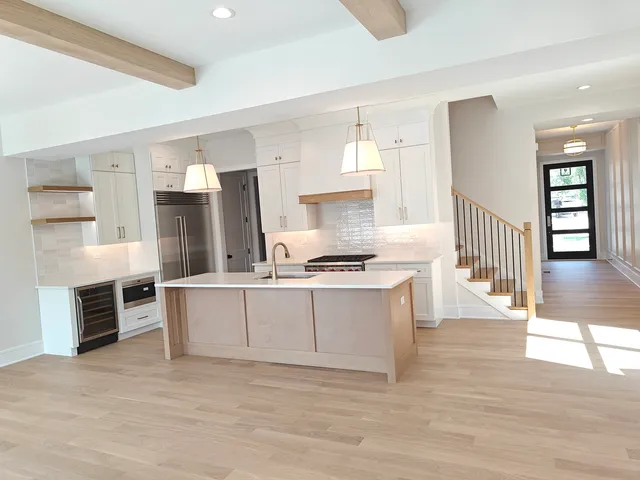 a large white kitchen with kitchen island a sink stainless steel appliances and cabinets