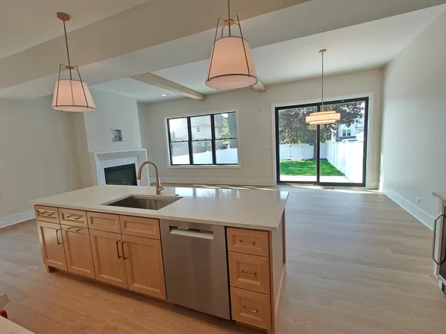 a kitchen with stainless steel appliances granite countertop a sink a microwave a dining table and chairs with wooden floor