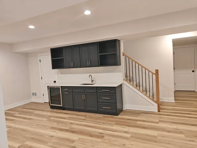 a view of an empty room with kitchen and wooden floor