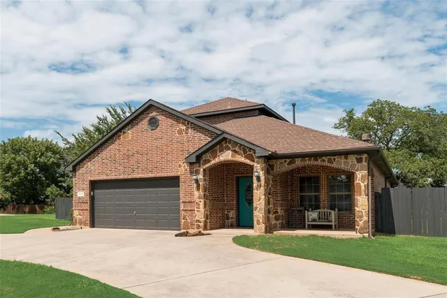 a front view of a house with a garden and trees