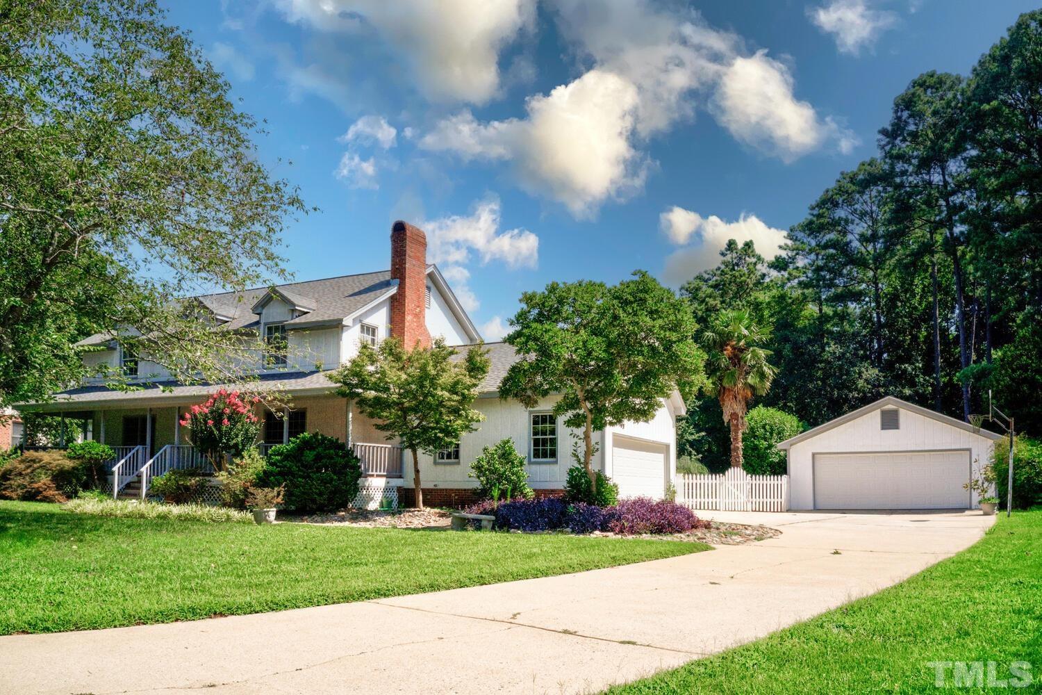 a front view of a house with a garden and trees