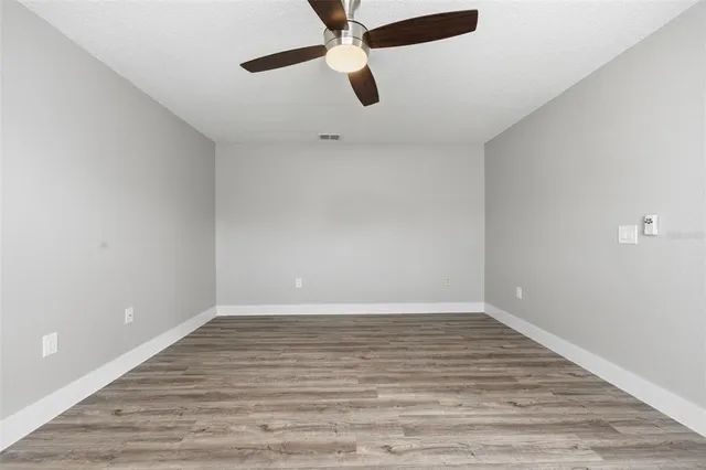 a view of an empty room with window and wooden floor