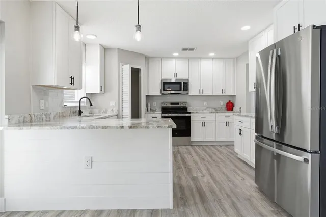 a kitchen with granite countertop white cabinets and a sink
