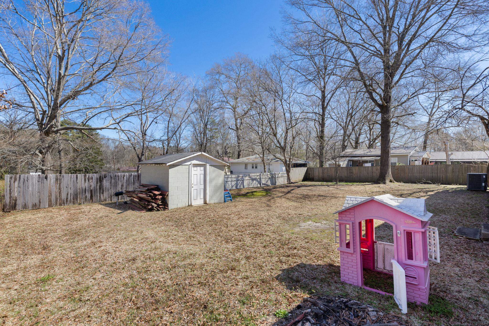 102 West 5th Street Iuka, MS 38852 - Photo 22 of 33 Expansive backyard featuring a storage shed, wood privacy fence, and mature trees