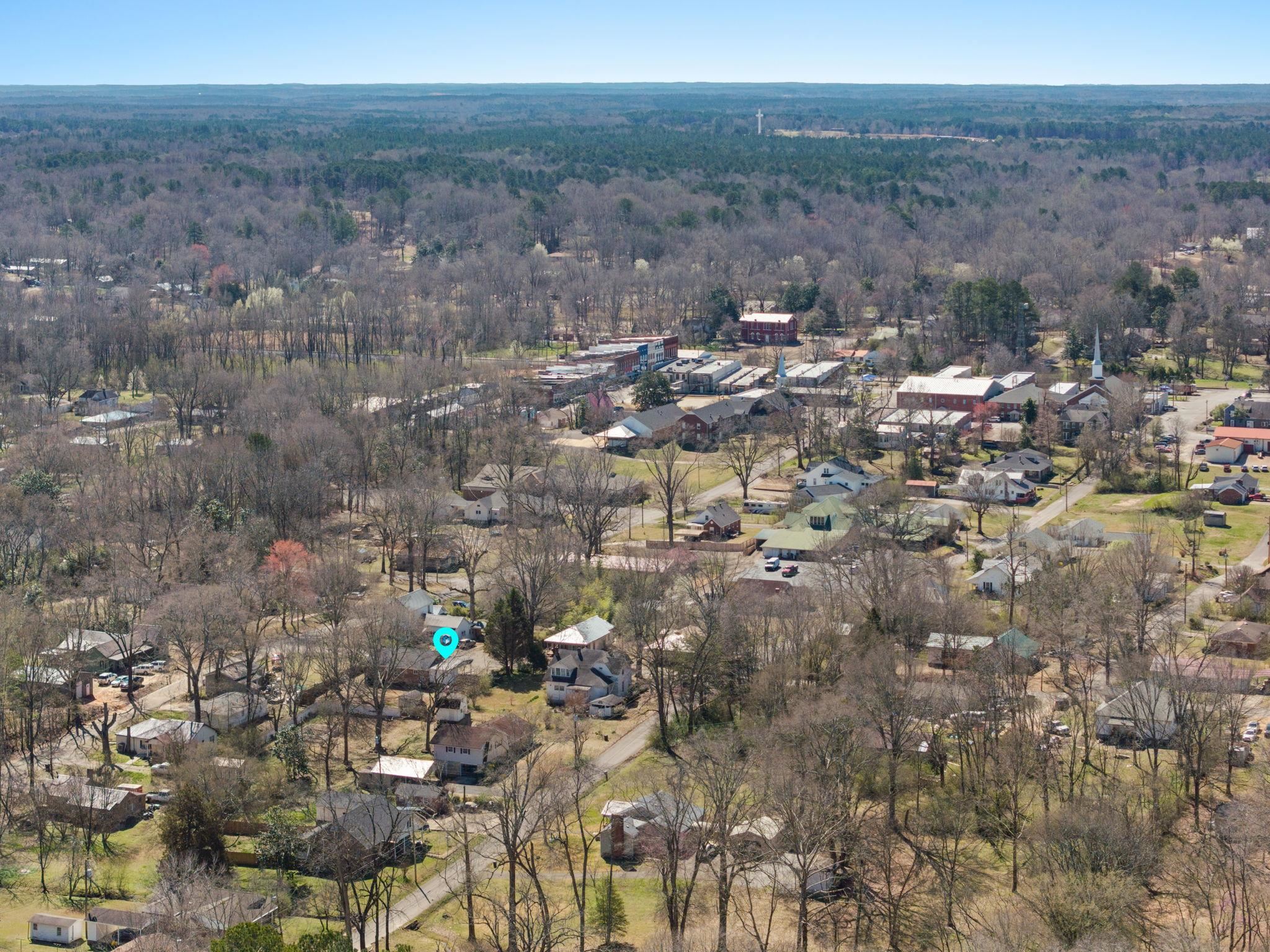 102 West 5th Street Iuka, MS 38852 - Photo 26 of 33 Aerial perspective showcasing a residential area with varied housing styles and extensive surrounding tree cover