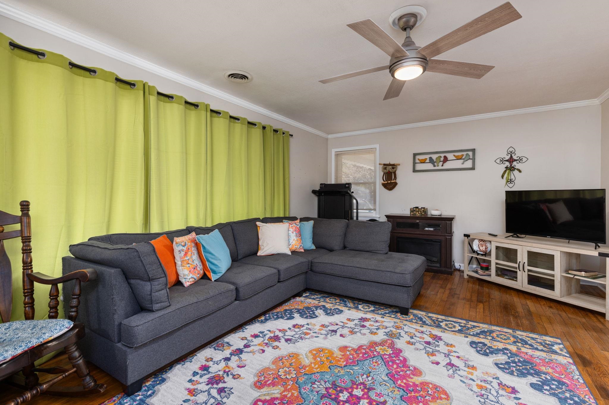 102 West 5th Street Iuka, MS 38852 - Photo 5 of 33 Spacious living area featuring wood-finish flooring, crown molding, and a ceiling fan with integrated lighting
